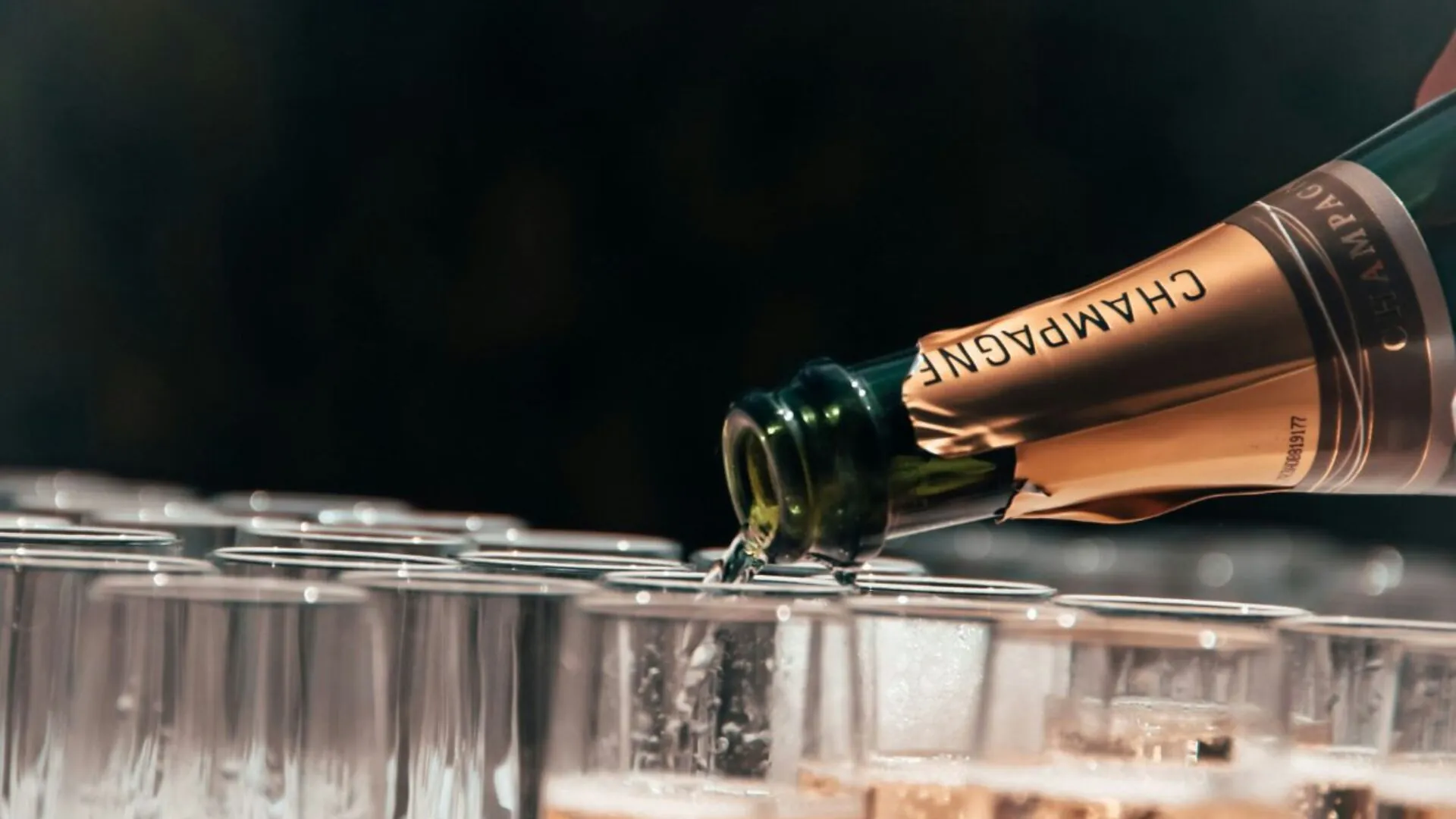 Champagne bottle with label pouring into glasses